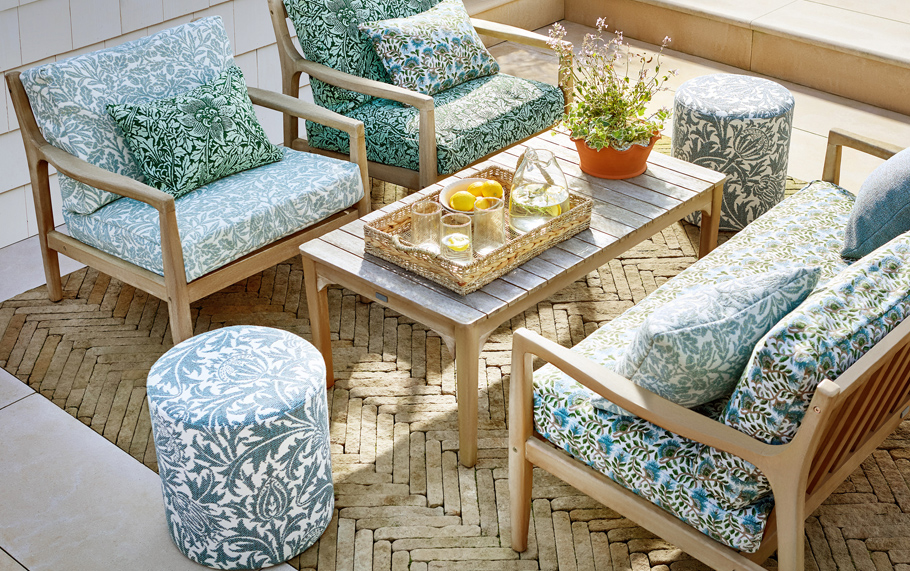 Hyggelig sittegruppe med puter trukket i Morris & Co sin nye inne ute tekstiler. Stolene er trukket med utendørstekstilene Thistle Acorn, sofaen er trukket i tekstilet Wardle Weaves.